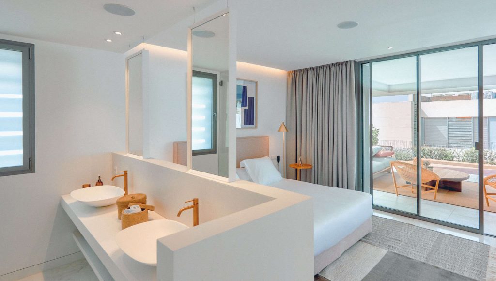 Un dormitorio principal lleno de luz. Dormitorio amplio y luminoso, con acceso directo a la terraza exterior. Baño abierto integrado en la habitación mediante un mueble de diseño.Ampliar
